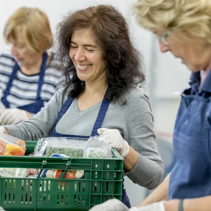 Frauen sortieren fröhlich Kisten mit Lebensmitteln 