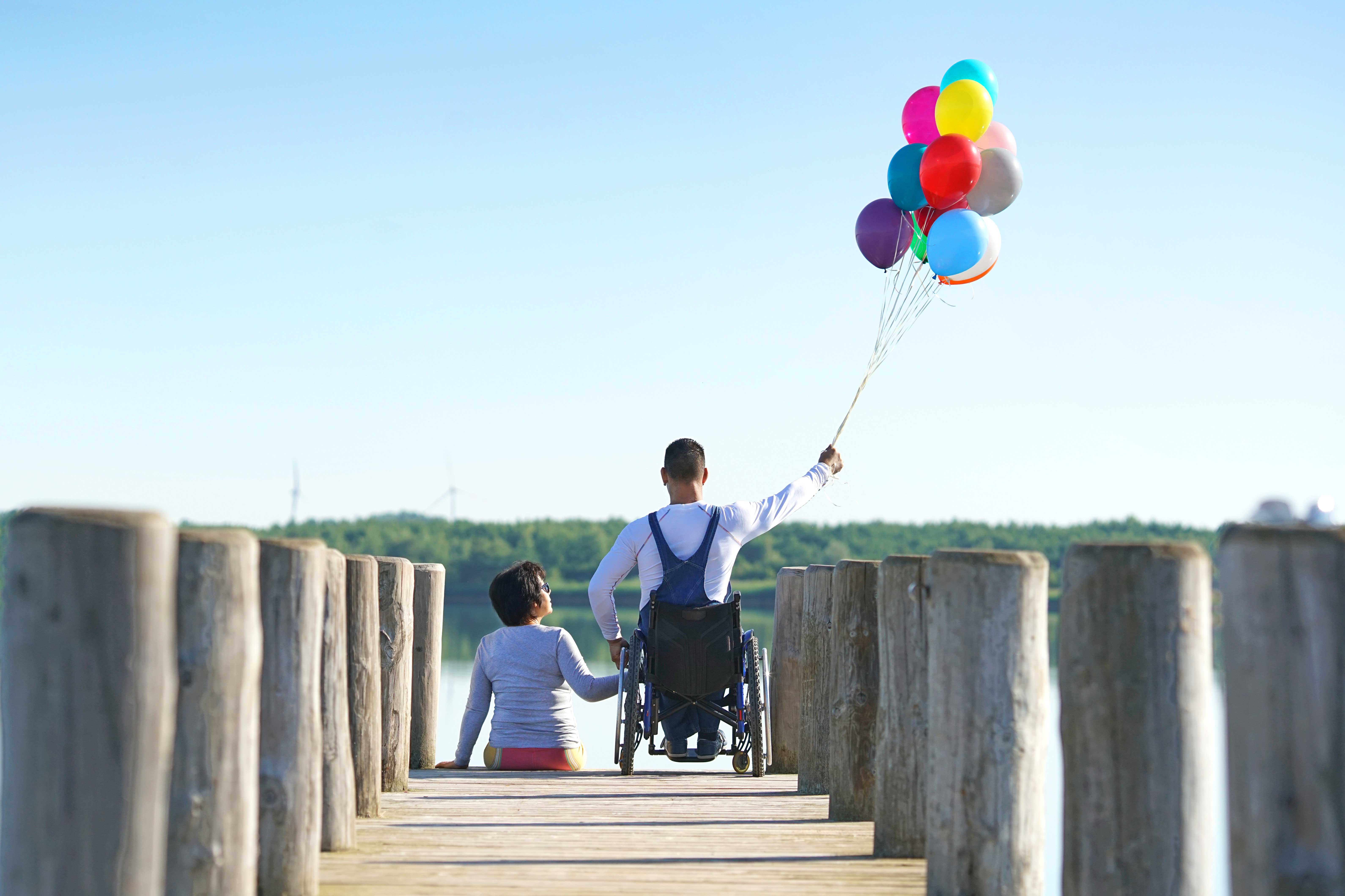 Mann in einem Rollstuhl, der Luftballons in der Hand hält